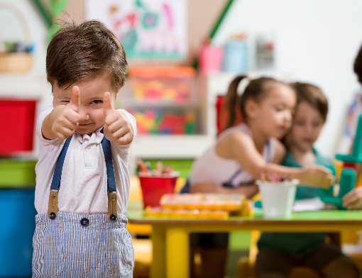 Criança fazendo sinal de "joia" dentro da sala de aula
