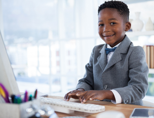 Criança negra de terno mexendo no teclado