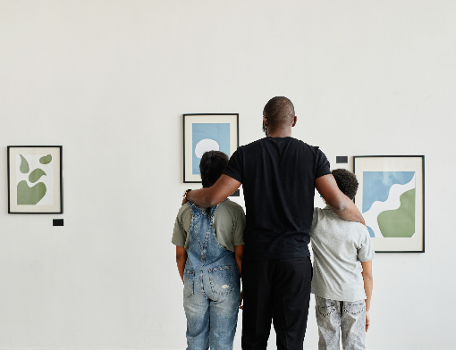 Pai e dois filhos observando quadros